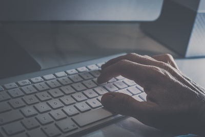 Hand typing on a modern design keyboard on the desk. view of fingers pressing the keys, soft focus