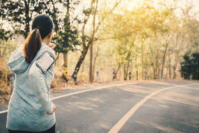 Woman running on road against trees