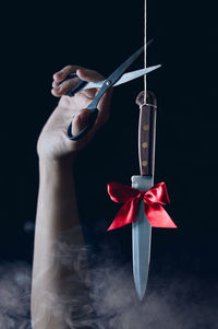 Midsection of woman holding umbrella against black background