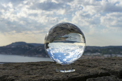 Close-up of crystal ball against sky