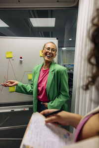 Happy businesswoman discussing while doing brainstorming with colleague at office