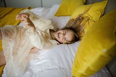 Beautiful little girl in stylish dress jumping on the bed with white blanket at home. stay at home 