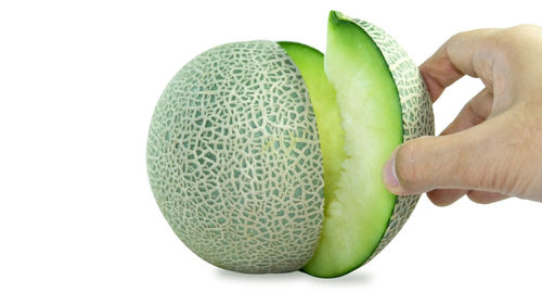 Close-up of hand holding fruit against white background