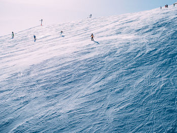 People skiing  on snow covered landscape against sky