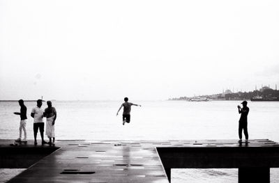 People standing on beach against clear sky