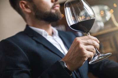 Midsection of businessman holding wineglass