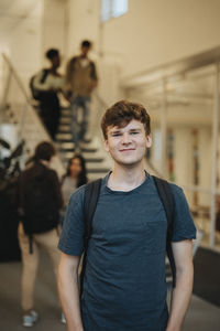 Portrait of smiling young male student standing in university