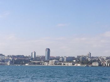 Sea by cityscape against sky