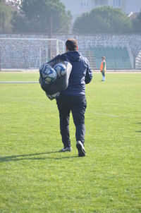 Rear view of man playing soccer on field