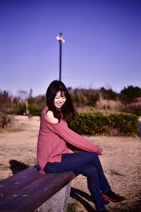 Portrait of woman sitting on field against sky