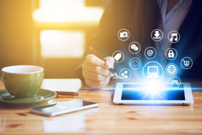 Midsection of man with pen using digital tablet with various icons in office