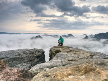 Hiker and photo enthusiast with tripod on cliff. peak with two men taking photos in autumn sunrise