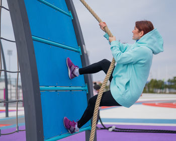 Full length of woman rope climbing at playground