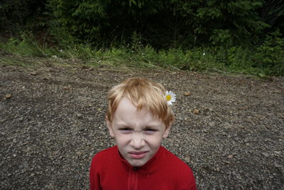 Portrait of boy wearing flower while standing on field