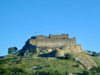 Low angle view of fort against clear blue sky