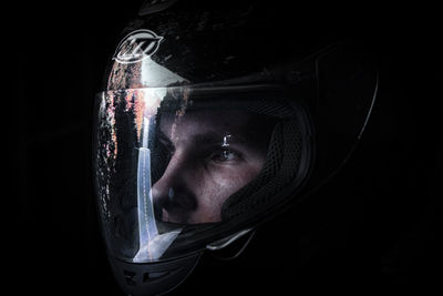 Close-up of man wearing mask against black background