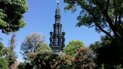 Low angle view of trees and tower against sky