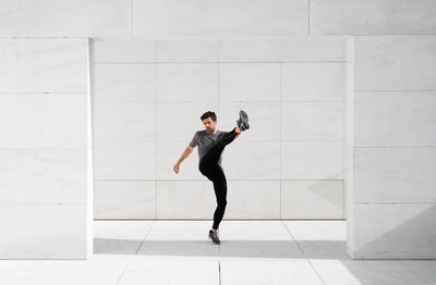 Side view of young man standing against wall