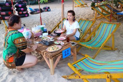 Rear view of two women sitting on table