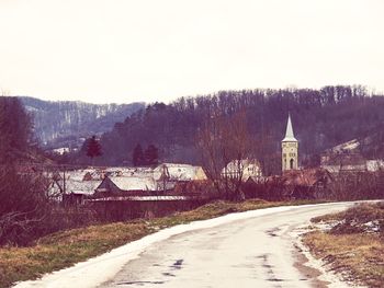 Road amidst trees against sky during winter