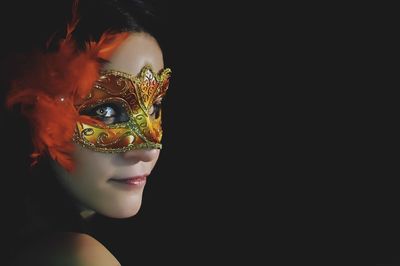 Portrait of woman wearing mask against black background