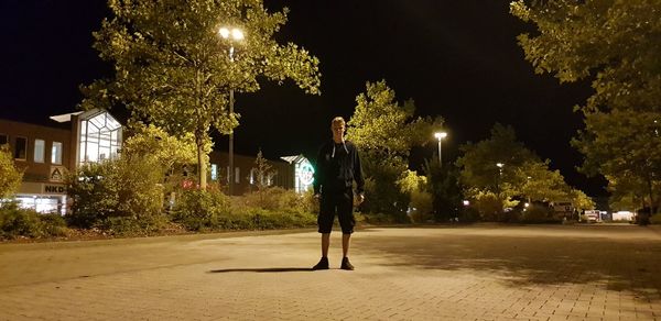 Man standing on illuminated street at night