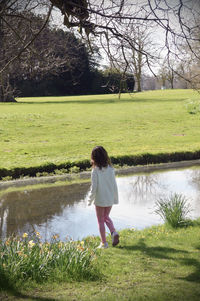 Rear view of woman standing by lake