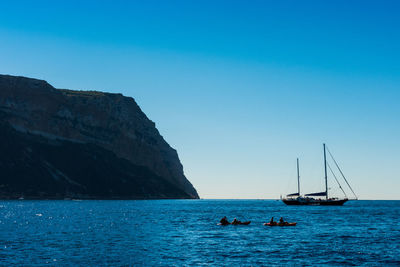 Sailboats sailing on sea against clear blue sky