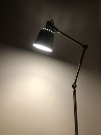 Low angle view of illuminated lamp against wall