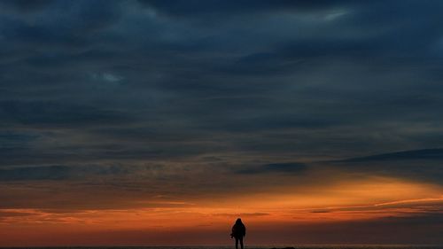 Silhouette of man against dramatic sky during sunset