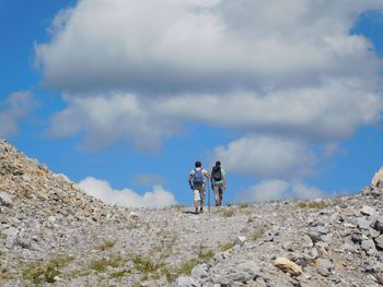 Low angle view of man standing on hill against cloudy sky