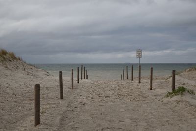 Wooden posts on beach against sky