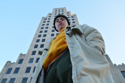 Low angle portrait of man standing against building in city