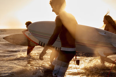 Surfers in the sea at sunset