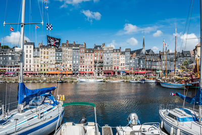 Boats moored at harbor against buildings in city