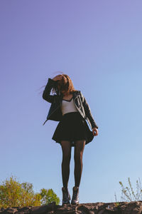 Low angle view of woman standing against clear sky