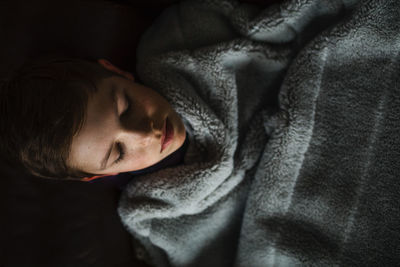 Teen boy cozy and covered in blanket