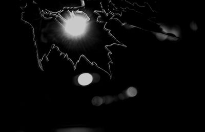 Low angle view of illuminated light bulb against black background