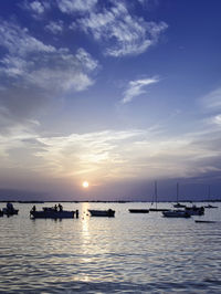 Boats in sea at sunset