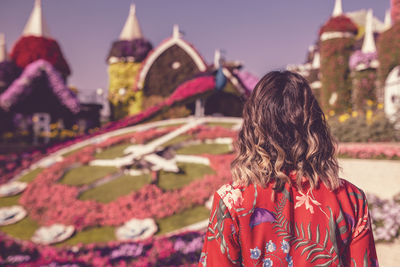 Rear view of young woman in ornamental garden at dusk