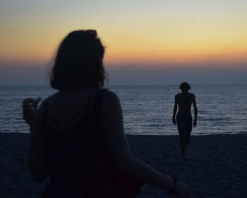 Rear view of women on beach during sunset