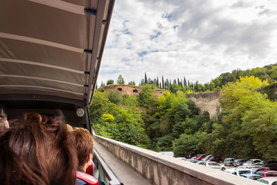 Rear view of woman looking at car against sky