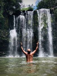 Full length of shirtless man splashing water