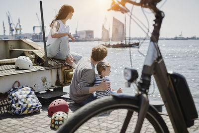 Germany, hamburg, family having a break from a bicycle tour at river elbe