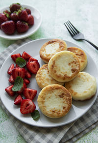 Cottage cheese pancakes, ricotta fritters on ceramic plate with fresh strawberry. 