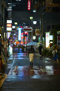 Rear view of woman walking on road at night