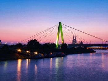 View of suspension bridge over river at sunset