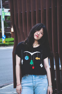 Portrait of young woman standing against wall