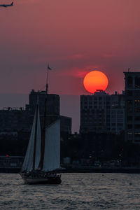 Sailboats in city at sunset