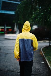 Rear view of person in raincoat walking on footpath